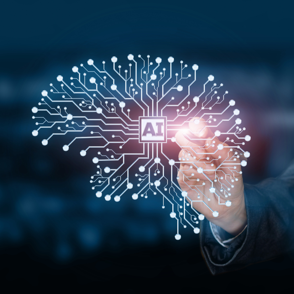 The image illustrates a digital concept of artificial intelligence (AI). A hand is shown touching a glowing circuit board design that resembles a brain, with the letters "AI" at the center.