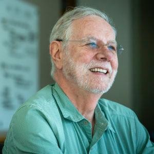 Photo of Dr. Ron Davis wearing a green t-shirt and smiling.